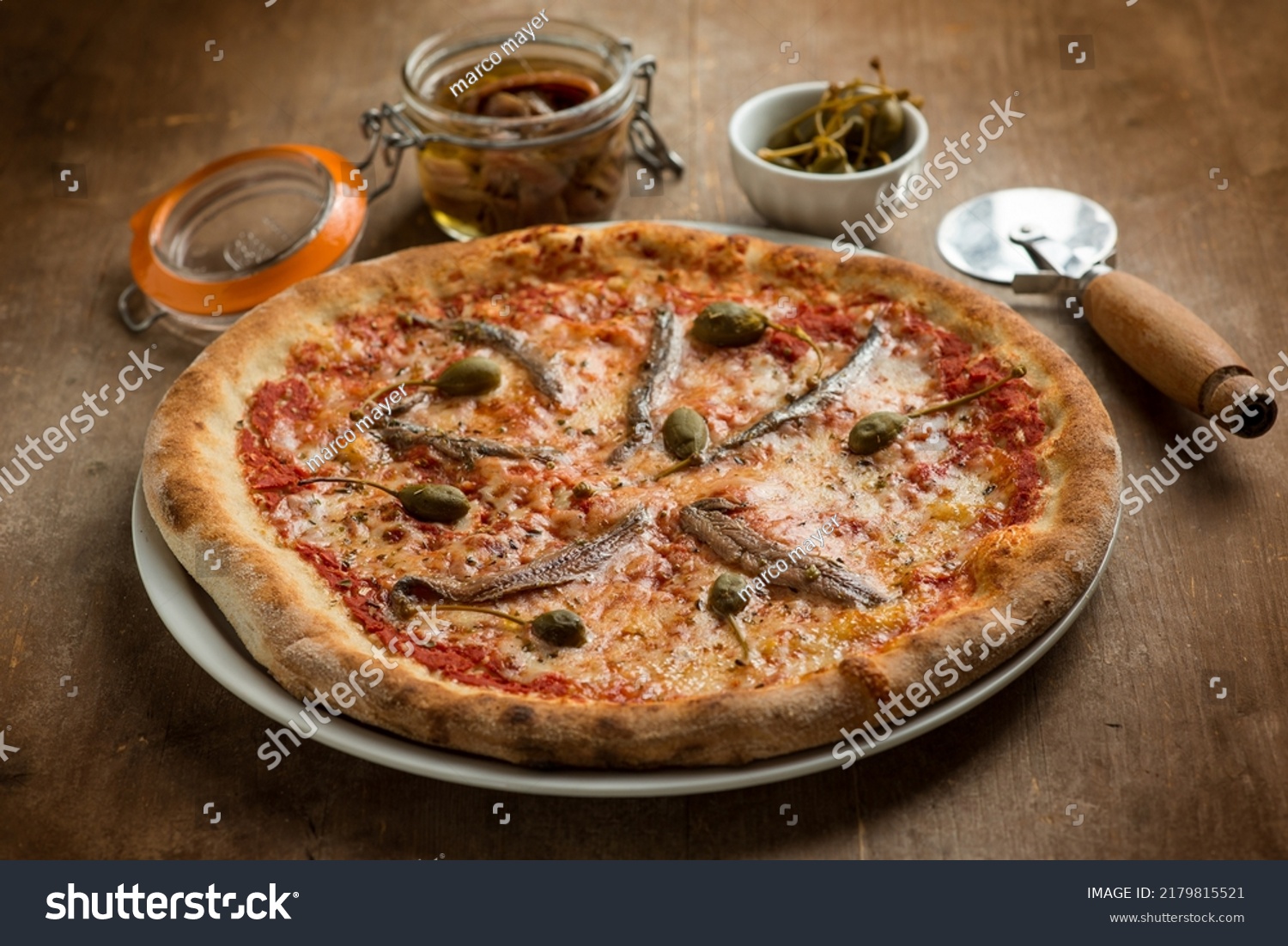 Pizza de salami y aceitunas verdes con alcaparras y tomates secos